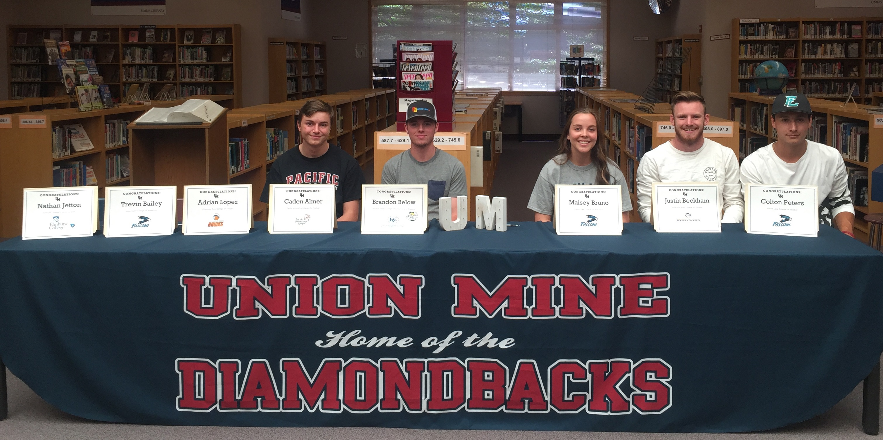 Athletics students showing off their certificates at a table